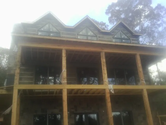 Dormers and porch framing on a large log home under construction — Roof Coating work by our crew in Woodsville