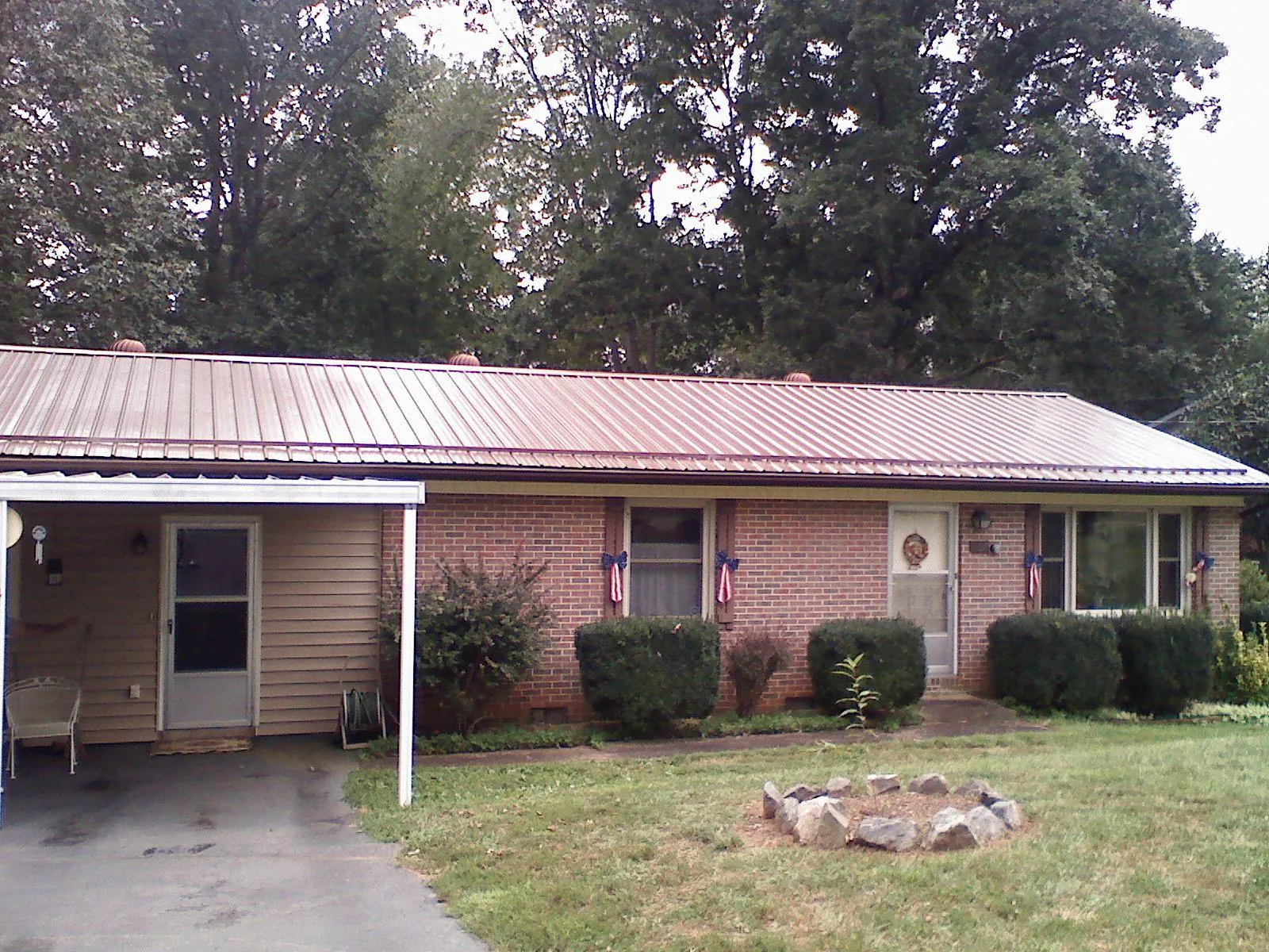 Bronze metal roof and carport on a brick ranch home — Roof Repair work by our crew in Woodsville