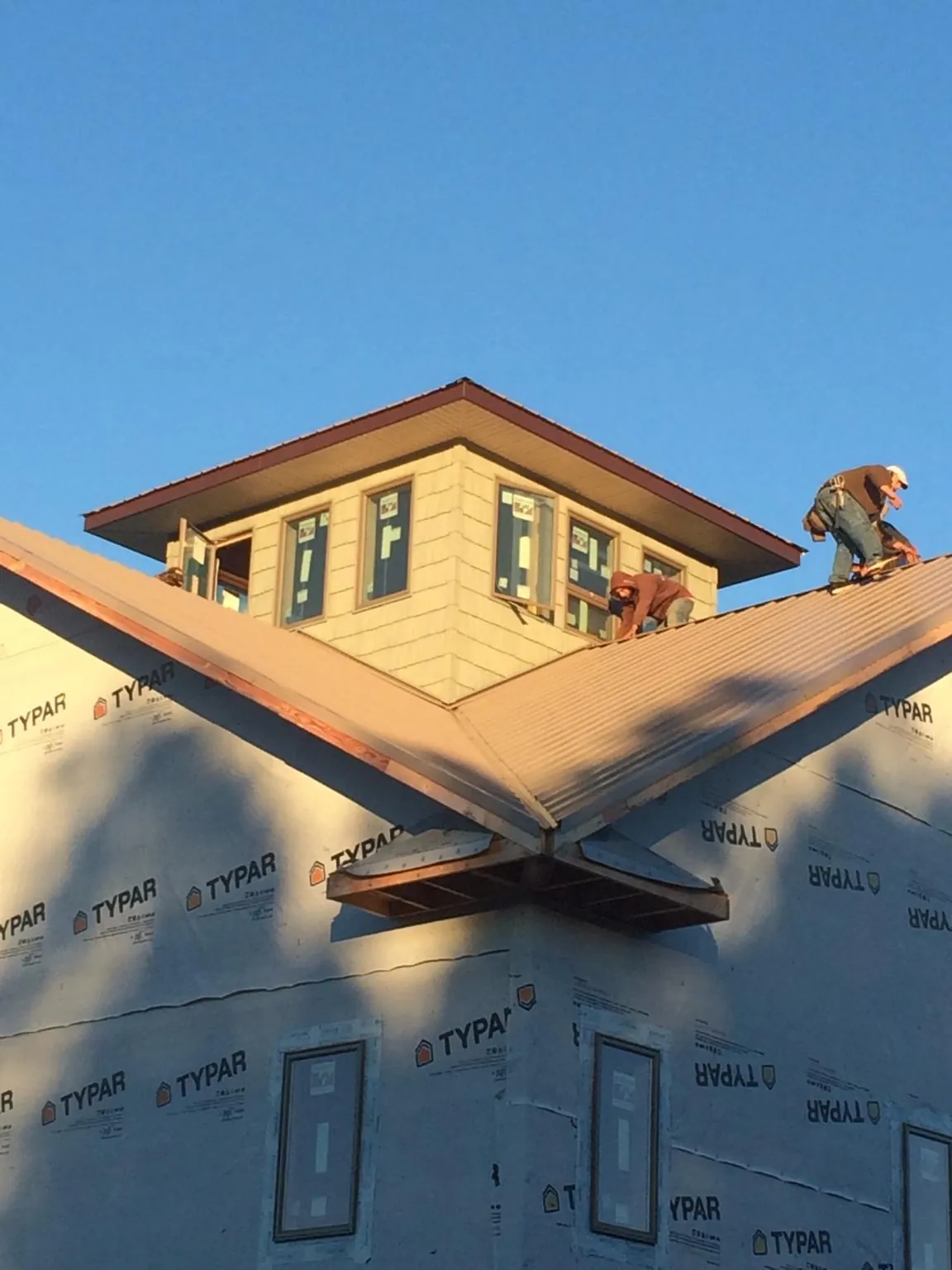 Roofers working around a rooftop cupola on a new metal roof at sunset — Roof Waterproofing in Woodsville by Roofing Brothers